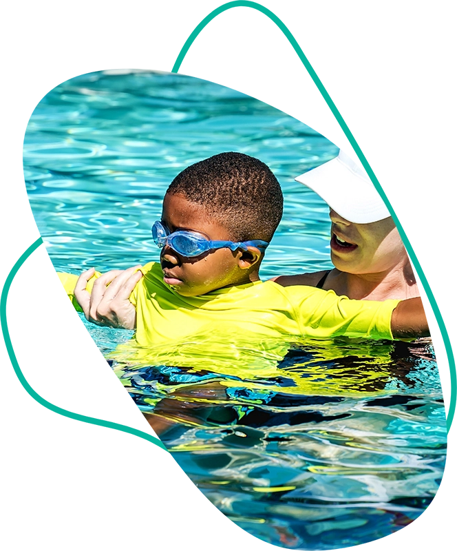 boy floating in pool with swimming instructor