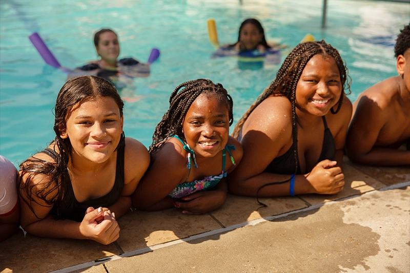 group of kids hanging out on a swimming pool ledge